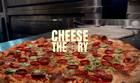 Cheese Theory pizza topped with peppers and peperoni in stainless steel kitchen